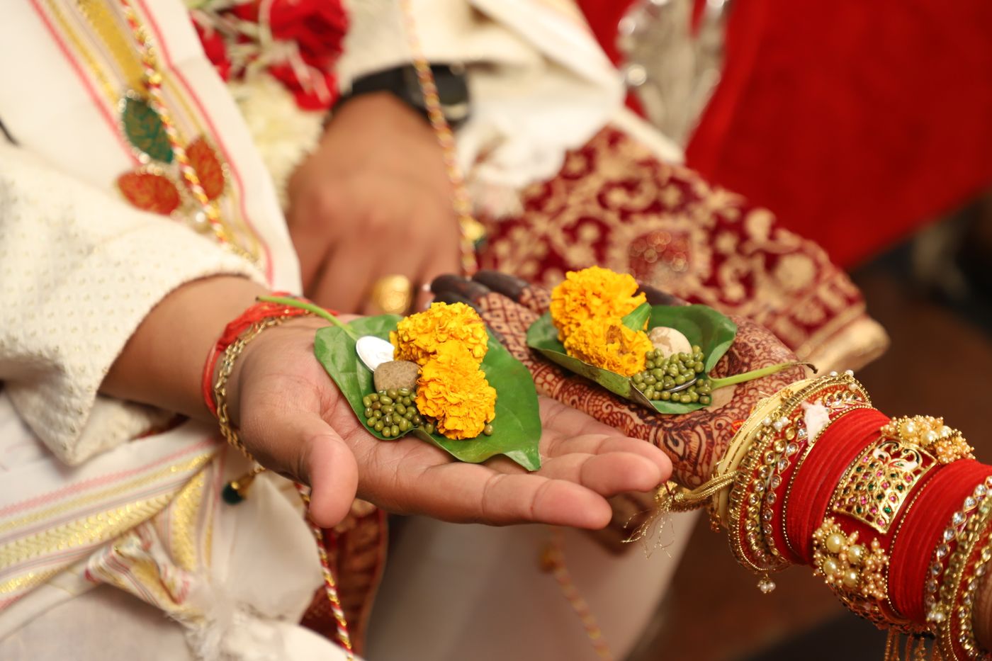 Hands holding betel leaves and flowers during a wedding ritual, inspiration photograph